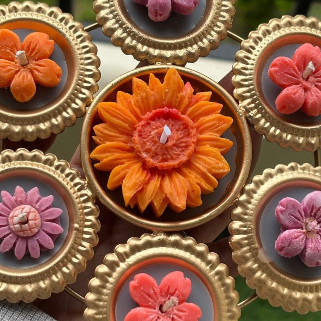 DH-03: Six flower diyas around one big orange bloom, joined in a gold metal frame, close-up of the big orange bloom.
