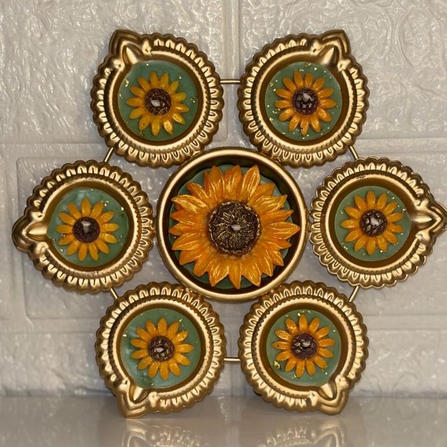 DH-04: Six sunflower diyas around one big sunflower, joined in a gold metal frame.