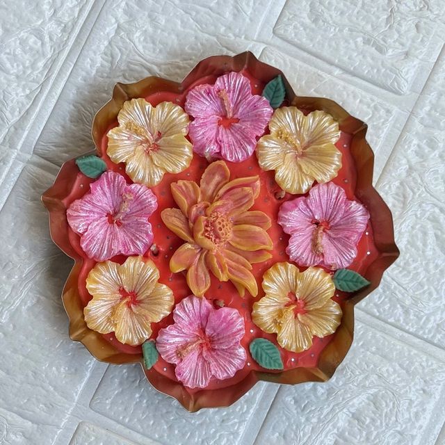 DH-06: Pink and yellow hibiscus around a lotus, in a scalloped metal tray, on a white table.