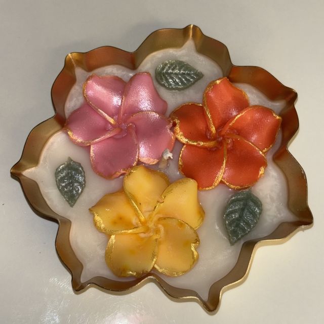 DH-09: Three plumeria blooms in a scalloped gold metal tray, from above.