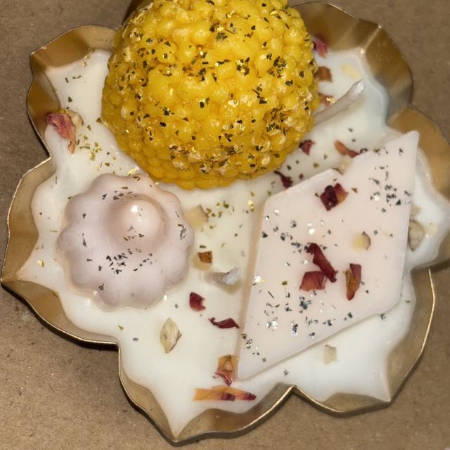 DH-11: Laddoo and barfi candles in a scalloped gold metal tray, close-up of the sweets.