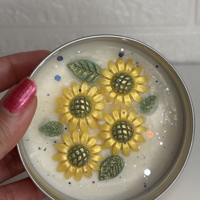 DH-15: Four sunflowers on ivory wax, in a metal tin, held in a hand, to show its size.