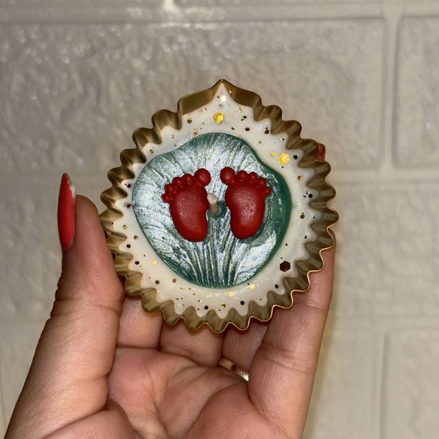 DH-16: A pair of diyas with Lakshmi’s footprints, in scalloped gold metal cups, one diya held in a hand, to show its size.